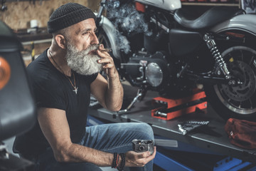 Wall Mural - Thoughtful mature man smoking in garage