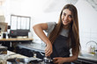 © Liubov Levytska - Young barista at work looking at camera smiling, using a tamper to prepare an espresso shot. Hipster work concept.