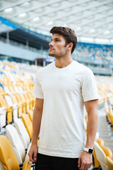 Poster - Sports man standing at the stadium outdoors and looking aside.