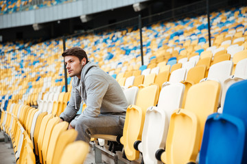 Poster - Serious young sports man at the stadium outdoors listening music