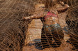 Mud race runners.Woman covered with mud fighting to get out of a net in the obstacle race