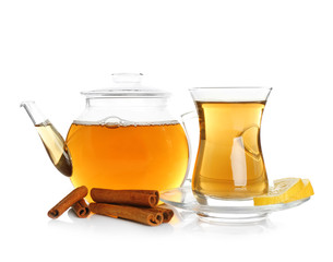 Poster - Glass teapot and cup with aromatic hot cinnamon tea on white background