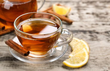 Poster - Cup with aromatic hot cinnamon tea and lemon on wooden table