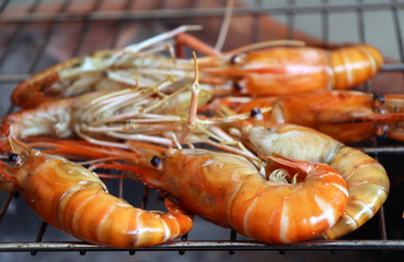 cook shrimp grilling on the metal grill grate in the thai charcoal stove. 