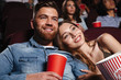 © Drobot Dean - Close up of a smiling young couple watching movie