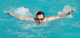 Fototapeta Łazienka - Young man with water goggles swim in a swimming pool, butterfly style