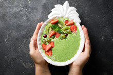 Woman Holding Smoothie Bowl With Kiwi, Spinach, Strawberries. Female Hands With Green Smoothie With Berries, Top View