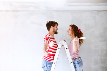 Wall Mural - Young couple painting walls in their new house.