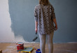 © Connect Images - Rear view of young woman looking at part grey painted interior wall at home