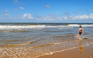 Wall Mural - Sea beach and boy playing with waves