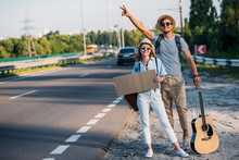 young couple in love with empty cardboard hitchhiking while traveling together