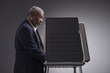 Portrait of a black man standing in a voting booth