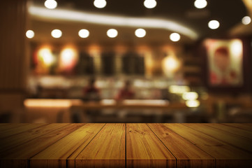 Wall Mural - Empty wooden table top with blurred restaurant or cafe light background.