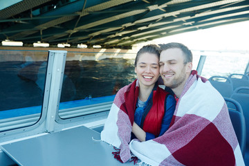 Canvas Print - Laughing man and woman wrapped in plaid traveling by motorship