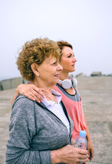 Wall Mural - Senior and young sportswoman looking away by sea pier