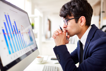 Side view of pensive man looking at financial chart in computer monitor