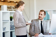 © pressmaster - Pretty young woman with cup of fragrant coffee chatting animatedly with her handsome bearded colleague, interior of modern office on background