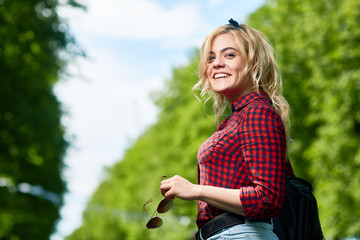 Wall Mural - Cheerful blonde girl with sunglasses looking at camera while relaxing in amusement park