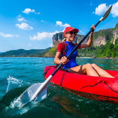 Wall Mural - Woman paddles red kayak in a tropical sea