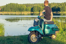Man Sitting On Restored Green Retro Motorbike Standing On A Meadow In The Afternoon