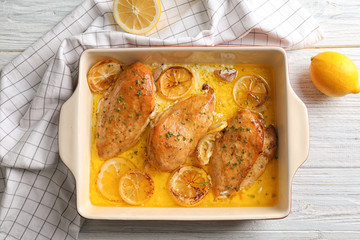 Delicious chicken breasts with lemon in baking dish on table