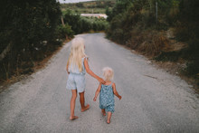 Two Little Sisters Walking Along The Road