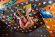 © Andrey Bandurenko - Young man bouldering in indoor climbing gym, solving challenging problem