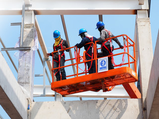 construction worker at construction site using lifting boom machinery