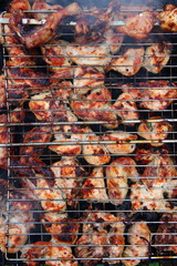 Pieces of chicken cooking on metal grill