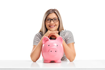 Sticker - Young woman with a piggybank sitting at a table