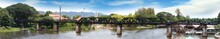 Panorama Of The Famous Bridge In Thailand, The Death Railway Bridge Of World War Ii On The Kwai River Kanchanaburi Buil By Japanese. Panorama Shot Of Kanchanaburi Kwai River.