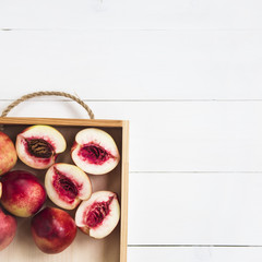 Wall Mural - Nectarines on a tray on a white table. Flat lay. Top view. Copyspace