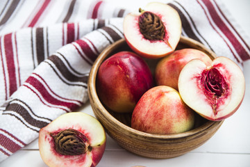 Wall Mural - Ripe nectarines in a clay dish white table