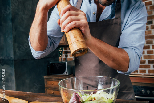 Cuadros en Lienzo cropped shot of man adding pepper with mill into salad