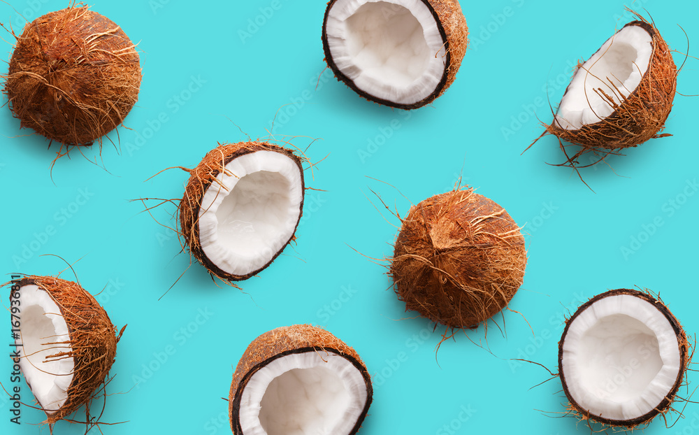 Coconut pattern on a blue background. Half and whole coconuts. Repetition concept. Top view - obrazy, fototapety, plakaty 