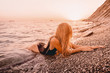 © artifirsov - Beautiful woman in black swimwear relax on sea with warm sunset colors.