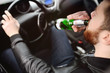 © Evgeniy Kalinovskiy - A young handsome bearded man with a bottle of beer or a low-alcohol drink at the wheel of a car. Driving in a state of intoxication