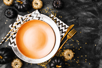 Canvas Print - Halloween Table setting on dark background. Dish on a dark table with black and gold pumpkin. Flat lay, top view trendy holiday concept.