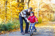Little kid boy and father with bicycle in autumn forest