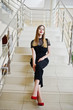 Portrait of a beautiful girl in fashionable designer clothes posing on the fly of stairs in the hotel or in the restaurant.