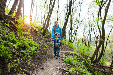 The boy and his mother are walking through the woods.