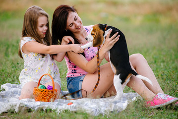 Young woman, her teenage little and their small beagle dog in the park