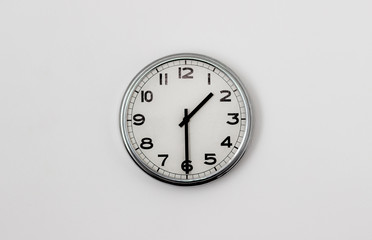 white clock hanging on a white wall showing time 1:30