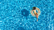 © Iuliia Sokolovska - Aerial view of girl in swimming pool from above, kid swim on inflatable ring donut and has fun in water on family vacation