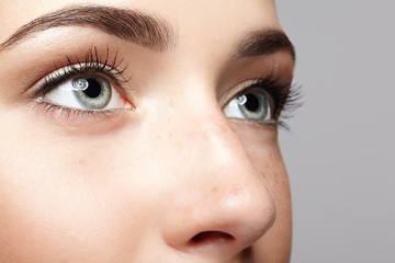 Closeup macro portrait of female face. Human woman open eyes with day beauty makeup. Girl with perfect skin and freckles