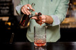 © fesenko - Bartender making alcoholic cocktail , metal jigger and bar environment