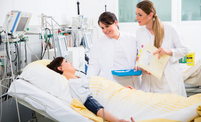 Canvas Print - Doctors visiting woman patient during medical round at ICU of hospital