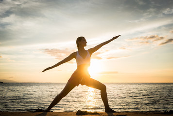 Wall Mural - Full length side view of the silhouette of a fit woman practicing the warrior yoga pose against sky at sunset during summer vacation in Flores Island, Indonesia