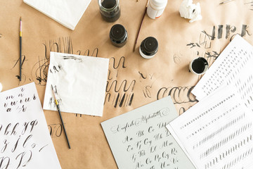 calligraphy, design, creativity concept. workspace preparing for practice in calligraphy with all requisite equipment such as ink of two color blac and white, brushes, lots of paper and few napkins