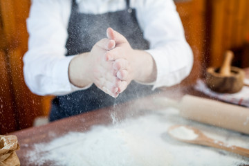 Man preparing bread dough on wooden table in a bakery close up